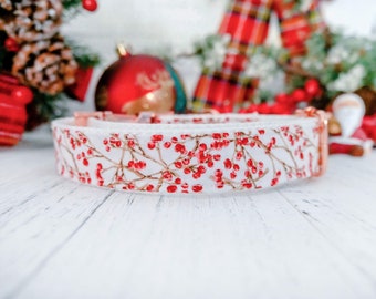 May include: White dog collar with a pattern of red berries on brown branches. The collar has rose gold hardware and is set against a festive holiday background with ornaments and greenery.