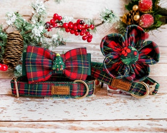 May include: A set of festive dog accessories in a red, green, and yellow plaid pattern. The set includes a collar, a bow tie with a Christmas tree, and a flower-shaped accessory. The accessories have gold-colored hardware and a brown leather tag.