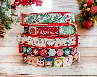 Puede incluir: Una pila de collares festivos para perros con diseños navideños. Los diseños incluyen copos de nieve, Papá Noel, renos y la palabra "Christmas". Cada collar tiene un borde rojo y un anillo de metal dorado.