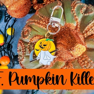 May include: A Halloween-themed keychain featuring a pumpkin with a ghost costume holding a scythe. The keychain has a silver clasp and the text "F. Pumpkin Killer" in orange. The background includes orange and green decorative elements.