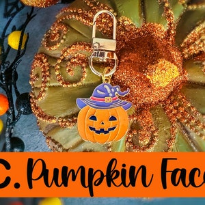 Pode incluir: Um chaveiro com tema de Halloween com um rosto de ab&oacute;bora laranja sorridente usando um chap&eacute;u de bruxa roxo e um fecho dourado. O texto "C. Pumpkin Face" &eacute; exibido em uma faixa laranja abaixo.