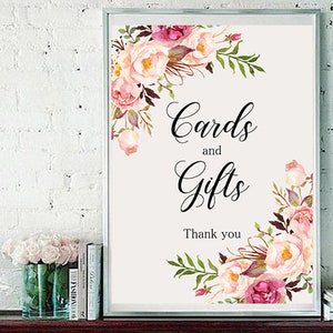 May include: A white sign with a floral border and the text "Cards and Gifts Thank you".