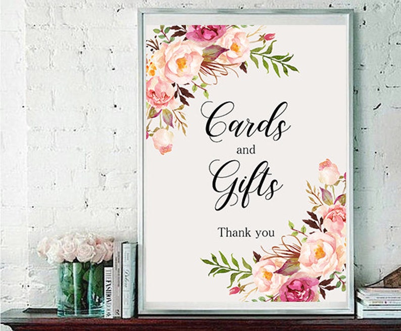 May include: A white sign with a floral border and the text "Cards and Gifts Thank you".