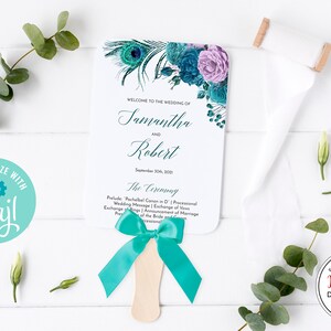 May include: A wedding fan with a teal ribbon and a wooden handle. The fan features floral and peacock feather designs in teal and purple, with the names "Samantha and Robert" and wedding details.
