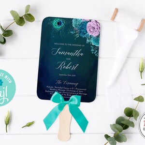 May include: A wedding fan with a teal and navy blue gradient background, decorated with floral accents and the names "Samantha and Robert." The fan includes the text "Welcome to the Wedding of" and "The Ceremony." A teal ribbon is tied to the wooden handle.