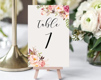 May include: A white table number card with floral designs in pink, red, and green. The card says "Table 1" in black cursive font.