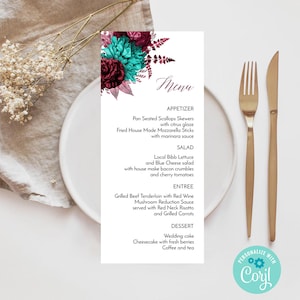 Puede incluir: Una tarjeta de menú de boda con un diseño floral en verde azulado y burdeos. El menú enumera opciones de aperitivos, ensaladas, entrantes y postres. Un tenedor y un cuchillo dorados se colocan a la derecha de la tarjeta en un plato blanco.