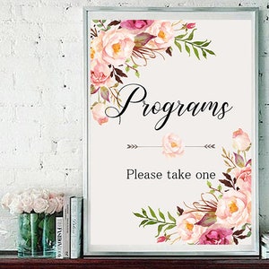 Puede incluir: Un cartel blanco con un borde floral y el texto "Programs" en negro. El cartel también dice "Please take one" en negro.