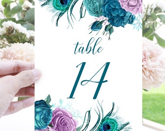 May include: A white table number card with teal blue and purple flowers and peacock feathers. The card says "table 14" in teal blue script.