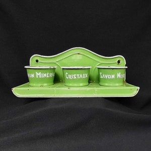 May include: A vintage green enamel wall-mounted organizer with three small pots. Each pot has white text: "Savon Noir", "Cristaux", and "Von Minéral". The organizer has a decorative top and a small shelf.
