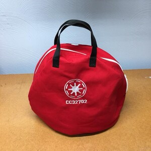 May include: Red round bag with a black handle and a white embroidered star symbol and the text "CC32702".