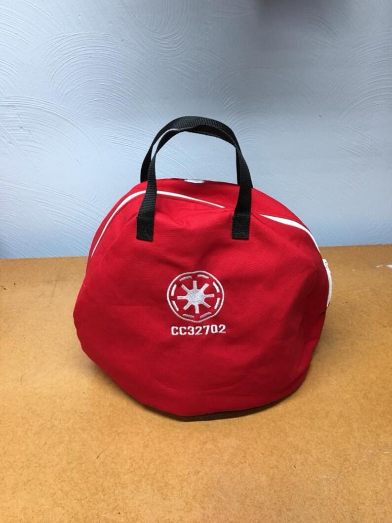 May include: Red round bag with a black handle and a white embroidered star symbol and the text "CC32702".
