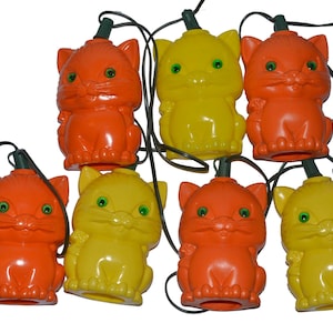 May include: A string of eight orange and yellow cat-shaped Christmas lights. The lights are connected by a green wire.