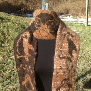 May include: A brown and white knitted scarf with a pattern of penguins and stars. The scarf is displayed on a mannequin.