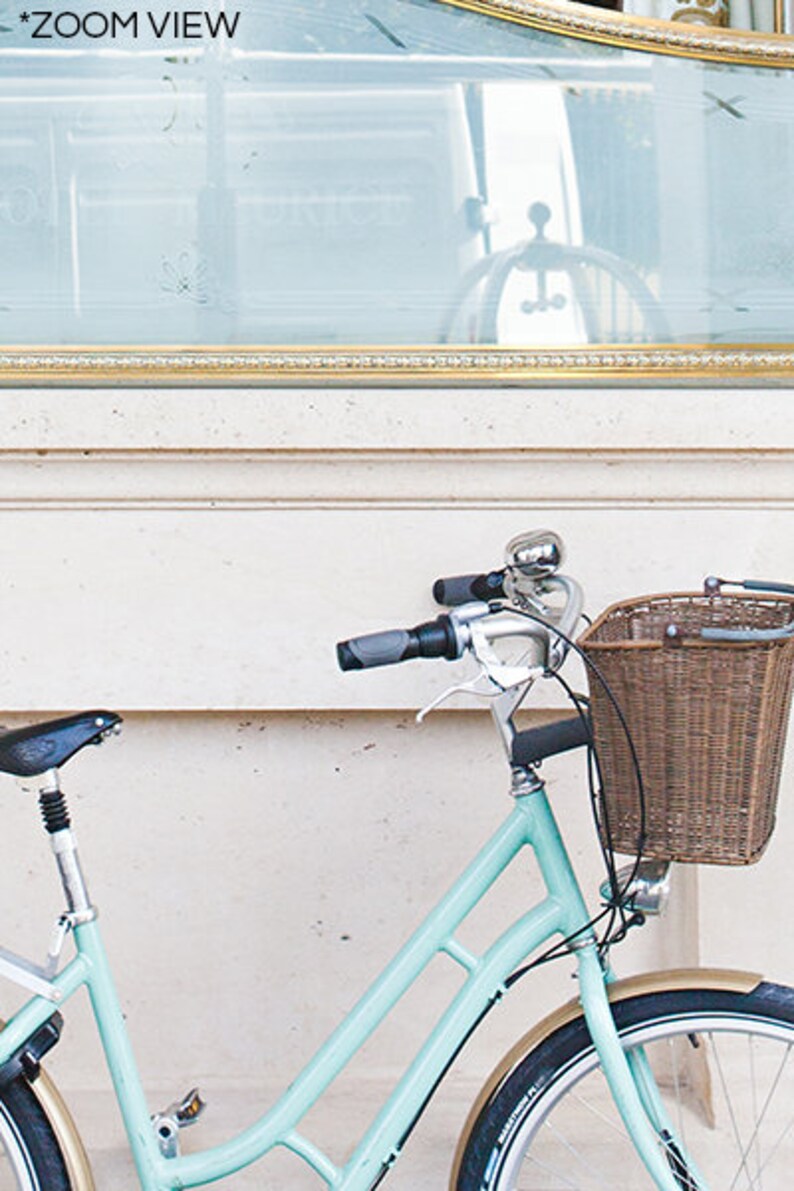 May include: A light blue bicycle with a wicker basket and a silver bell. The bicycle has a black seat and tires with tan sidewalls. The handlebars have gray grips. The text "*ZOOM VIEW" is in the top left corner.