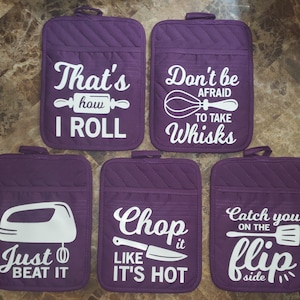May include: Set of six purple pot holders with white text and images. The text on the pot holders reads: "That's how I roll", "Don't be afraid to take whisks", "Just beat it", "Chop it like it's hot", and "Catch you on the flip side".