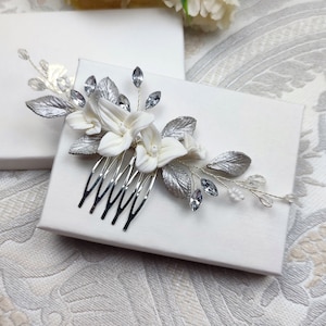 Peigne à cheveux floral avec fleurs blanches et feuilles argentées en porcelaine froide, cristal et strass transparent et perles de rocailles pour chignon ou coiffure de mariage bohème champêtre chic