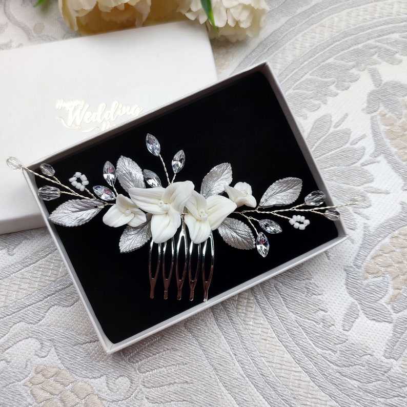 Peigne à cheveux floral avec fleurs blanches et feuilles argentées en porcelaine froide, cristal et strass transparent et perles de rocailles pour chignon ou coiffure de mariage bohème champêtre chic