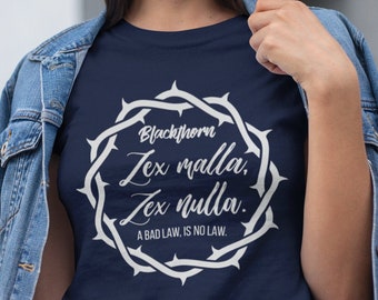 May include: A navy blue t-shirt with a white graphic of a crown of thorns and the text "Blackthorn Zex malla, Zex nulla. A BAD LAW, IS NO LAW."