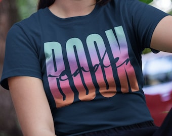 May include: A navy blue t-shirt with a rainbow gradient graphic that says "Book reader" in a stylized font.