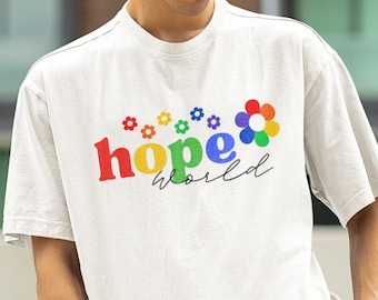 May include: A person wearing a white t-shirt and black pants. The t-shirt has the words "hope world" in colorful letters with flower graphics. A black bucket hat with a flower graphic is also worn.