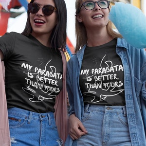 May include: Two friends wearing black t-shirts with the text "My Paradata is Better Than Yours" printed on them. They are holding pink and blue cotton candy and smiling at the camera.