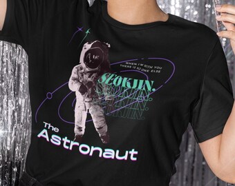 May include: Black t-shirt with a graphic of an astronaut in a space suit. The text "When I'm with you there is no one else" and "The Astronaut" are printed on the shirt.