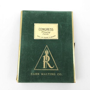 May include: A green playing card case with gold trim. The case has a rectangular label that reads "CONGRESS Playing Cards" and "CEL-U-TONE FINISH". Below the label is a triangle with the letter "R" and the text "RAHR MALTING CO."