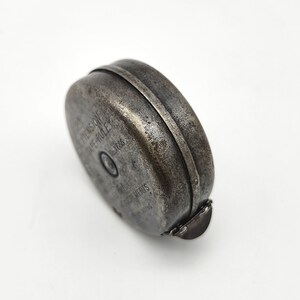 May include: A vintage silver-colored metal tape measure with the text "EXTENSION TAPE-RULE" and "Made in England" on the side.