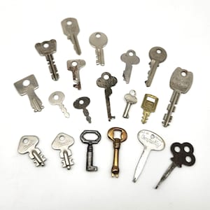 May include: A collection of various vintage keys in different shapes and sizes, made of metal. Some keys are silver, others are tarnished with age, and one is gold-toned. The keys are arranged on a white background.