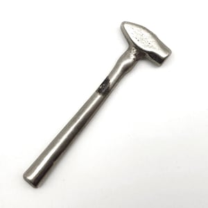 May include: A small, solid metal hammer with a smooth, cylindrical handle and a tapered, wedge-shaped head. The tool features a uniform silver-toned finish with a dark, weathered patch of discoloration located on the upper portion of the handle.