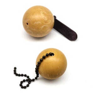 May include: Two light tan, spherical objects with a smooth, marbled texture. One sphere is attached to a dark brown, flat, rectangular tab. The other sphere features a small hole with a black metal ball chain extending from it.