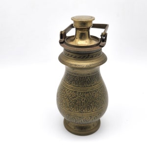May include: A brass container with an ornate floral design and a hinged lid. The container has a handle on the top and a round base.