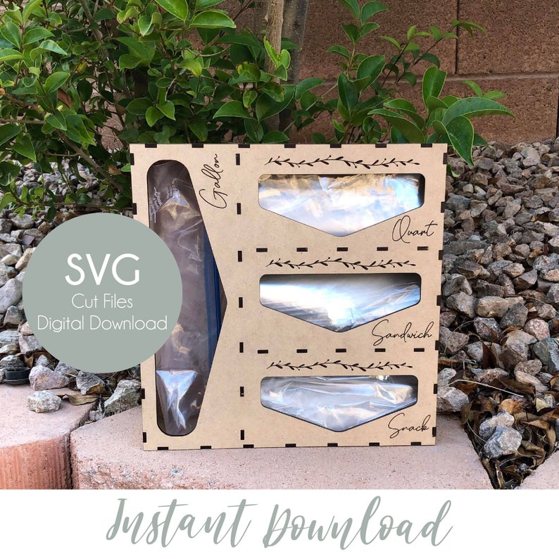 May include: A wooden storage organizer for plastic bags, labeled for gallon, quart, sandwich, and snack sizes. The design includes decorative leaf accents and the text "Instant Download" and "SVG Cut Files Digital Download".