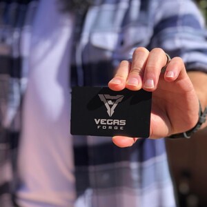 Matte black metal business card with engraved QR code and logo design.