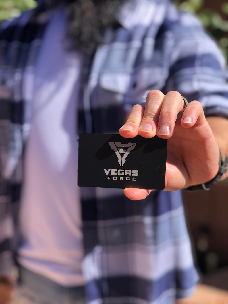 Matte black metal business card with engraved QR code and logo design.