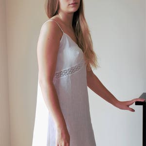 May include: A white linen slip dress with a lace trim. The dress has a simple, classic design and is perfect for a casual or formal occasion.