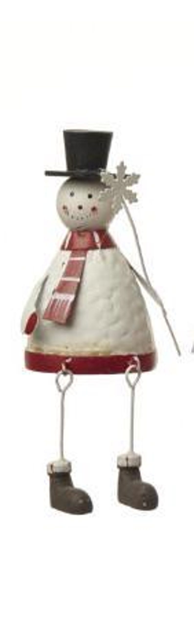 Puede incluir: Figura de mu&ntilde;eco de nieve de metal con sombrero de copa negro, bufanda roja y base roja. El mu&ntilde;eco de nieve sostiene una varita de copo de nieve y tiene botas marrones. Una decoraci&oacute;n festiva de invierno.