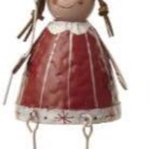 Puede incluir: Figura decorativa de metal de una ni&ntilde;a. Lleva un gorro c&oacute;nico rojo con un pomp&oacute;n blanco y un vestido rojo a juego. La figura tiene piernas, brazos y botas marrones de alambre. La cara est&aacute; pintada con una expresi&oacute;n sonriente. Un adorno encantador.
