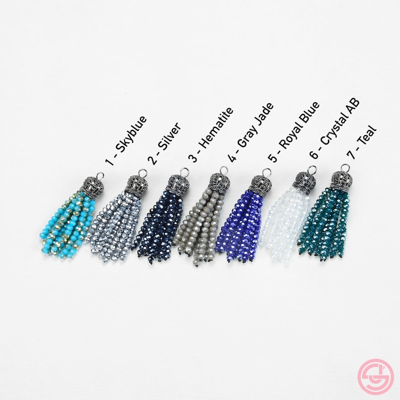 May include: Seven different colored crystal tassel charms with silver metal tops. The tassels are in the colors sky blue, silver, dark blue, gray, royal blue, clear crystal, and teal.
