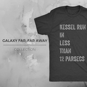 Op de afbeelding: Een donkergrijs T-shirt met de tekst "Kessel Run in Less Than 12 Parsecs" gedrukt op de voorkant. De tekst is in een wit, verweerd lettertype. Het T-shirt maakt deel uit van een "Galaxy Far, Far Away" collectie.