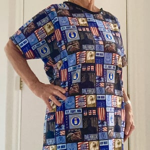 Op de afbeelding: Een blauw en rood T-shirt met een patchwork-ontwerp met het Air Force-logo, Amerikaanse vlaggen en de woorden "Fly, Fight, Win" en "Aim High".