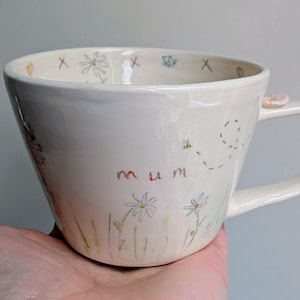 May include: A trio of ceramic mugs with a speckled, matte finish in cream, light grey, and dark grey. Each mug features a simple, minimalist design, ideal for tea or coffee.
