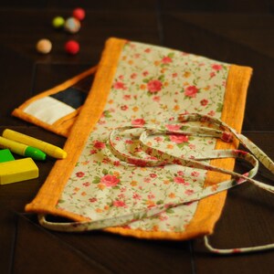 May include: A floral fabric pouch with a yellow trim and a white background. The pouch has a drawstring closure and is perfect for storing small items.