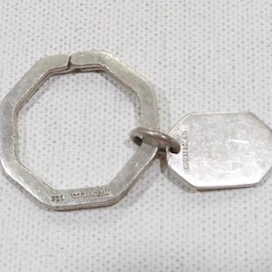 May include: A silver octagonal key chain with a silver tag that reads "TIFFANY & CO. 925".