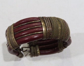 Prachtige dieprode leren armband in manchetstijl met overal koperen banden