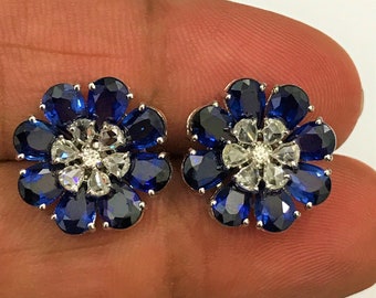 Op de afbeelding: Een paar bloemvormige oorbellen met blauwe en witte edelstenen. De oorbellen zijn gemaakt van zilver en hebben een delicaat ontwerp.