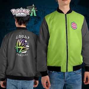 Könnte beinhalten: Zweifarbige Bomberjacke mit schwarzem Kragen, Bündchen und Saum. Die Vorderseite ist limettengrün mit einem rot-weißen Emblem, während die Ärmel grau sind. Die Rückseite der Jacke ist grau mit einer farbenfrohen Grafik und Text.