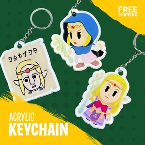 May include: Acrylic keychains featuring cartoon characters. One keychain shows a character on a scroll with Japanese text. Other keychains depict a character in a blue hood and another in a purple dress. The keychains are attached to silver keyrings.