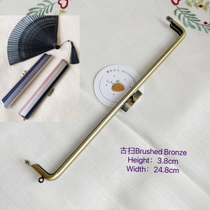 May include: Brushed bronze purse frame with a height of 3.8 inches and a width of 9.8 inches. The frame is made of metal and has a smooth finish.